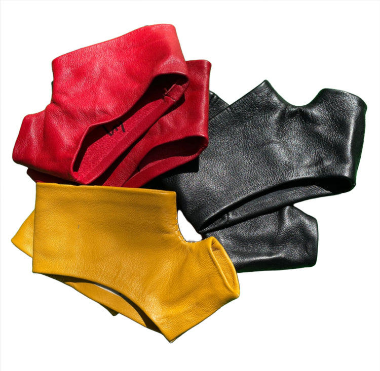 three mini gloves in Black, red, mustard color on a grass green wood floor 