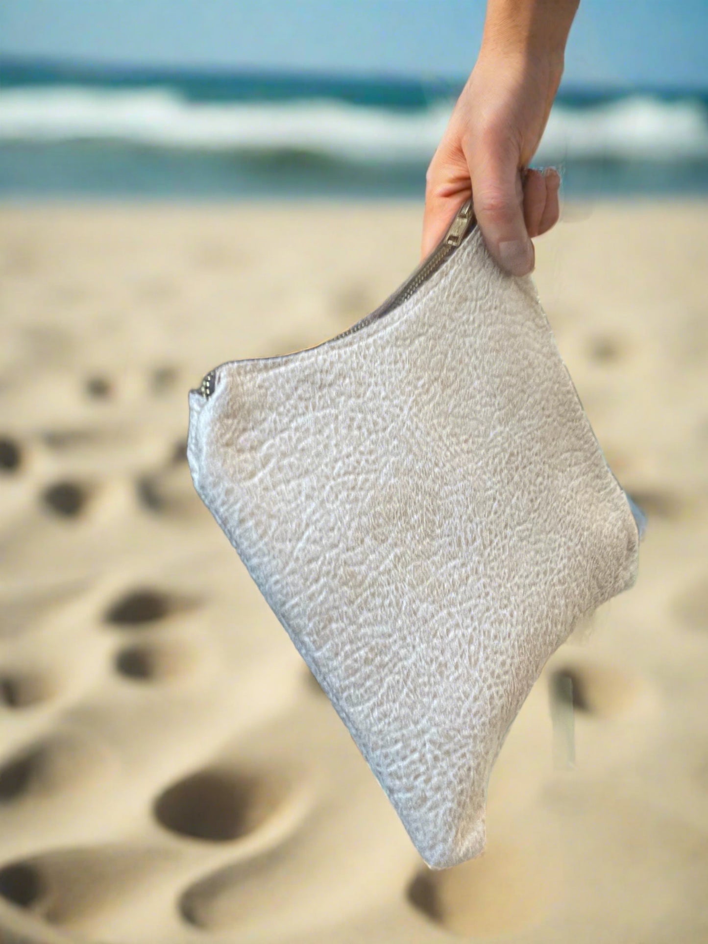 woman hand on the Beach holding a Beige handbag with a zipper