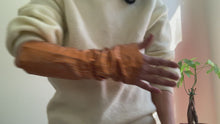 Load and play video in Gallery viewer, woman showing with her hands how to wear lamia design orange leather arm warmers