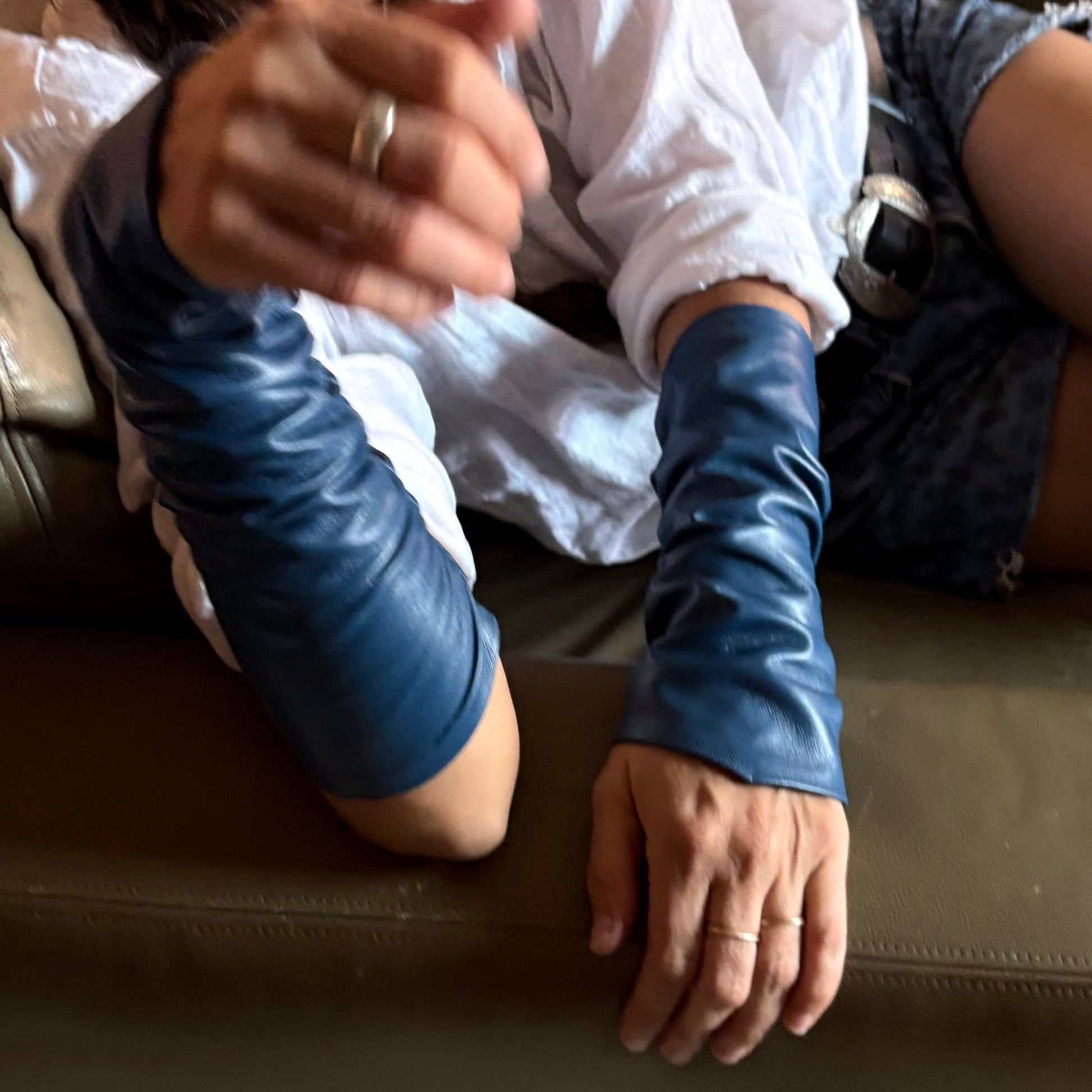 Woman wearing blue long-sleeve gloves sitting on a couch.