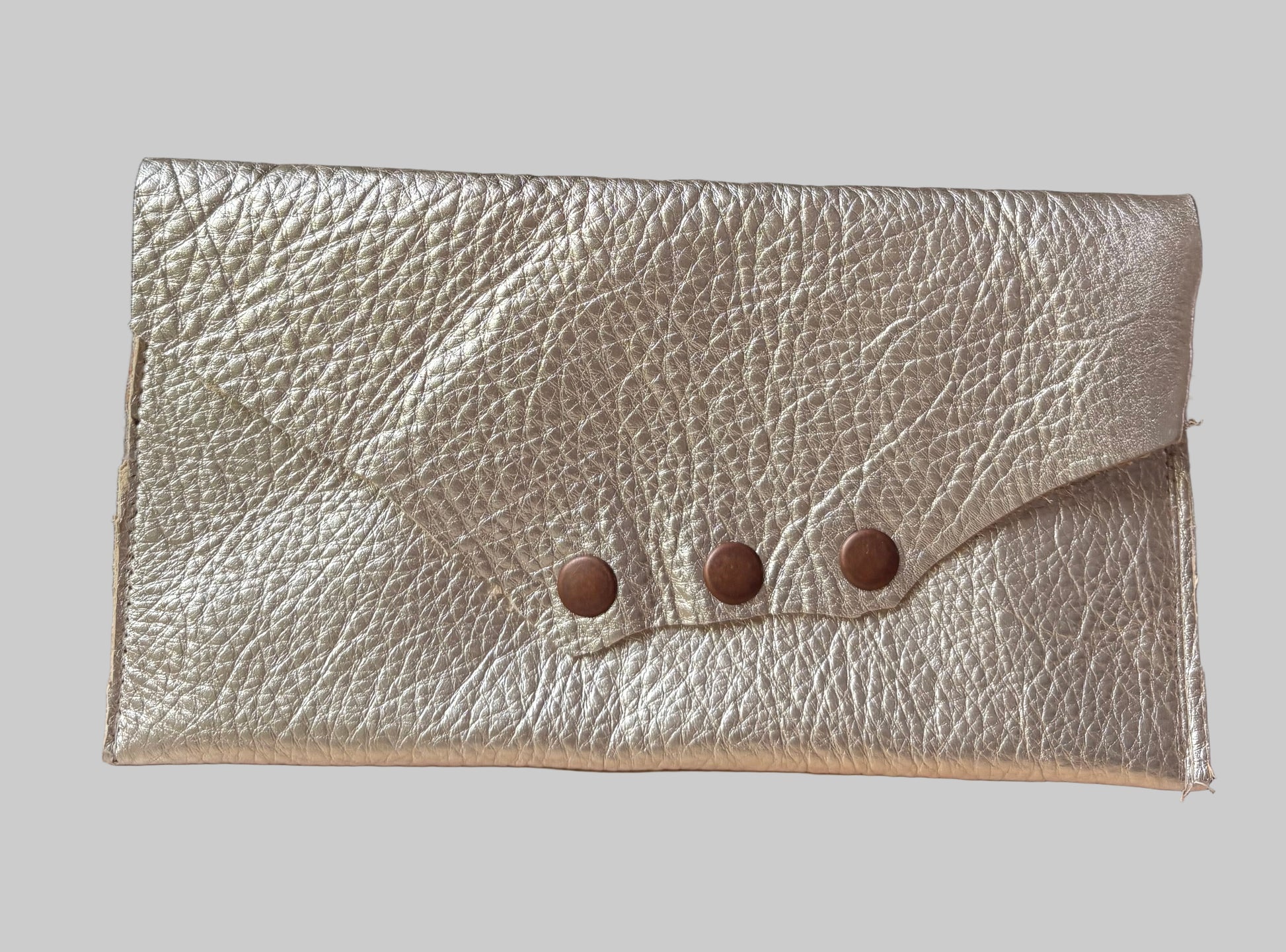 Gold leather clutch with button details on a wooden surface
