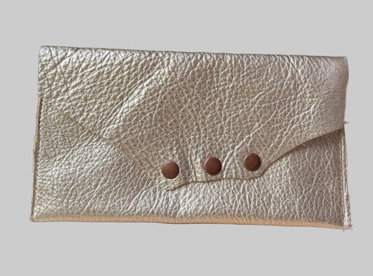 Gold leather clutch with button details on a wooden surface